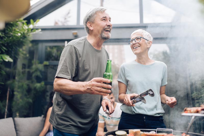 Smiling man and woman grilling outdoors